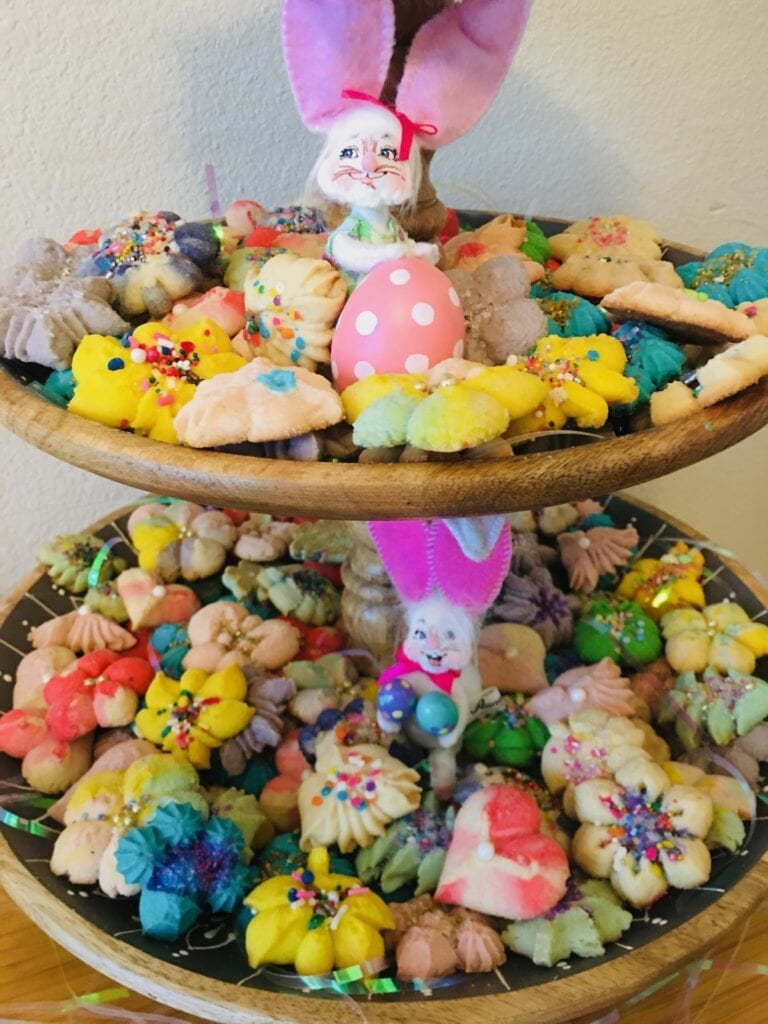 A wooden bowl filled with different colored cookies.
