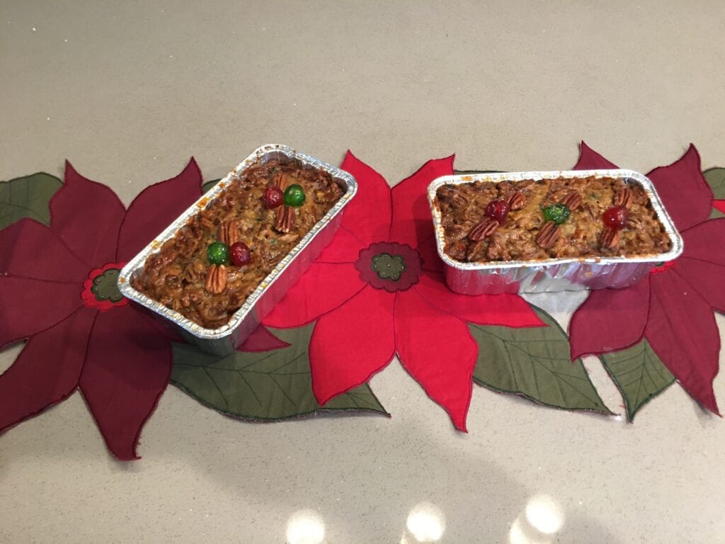 Two dishes of food on a table with poinsettia decorations.