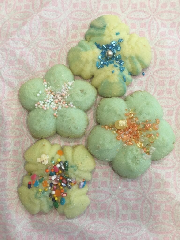 A group of green cookies with different colored sprinkles.