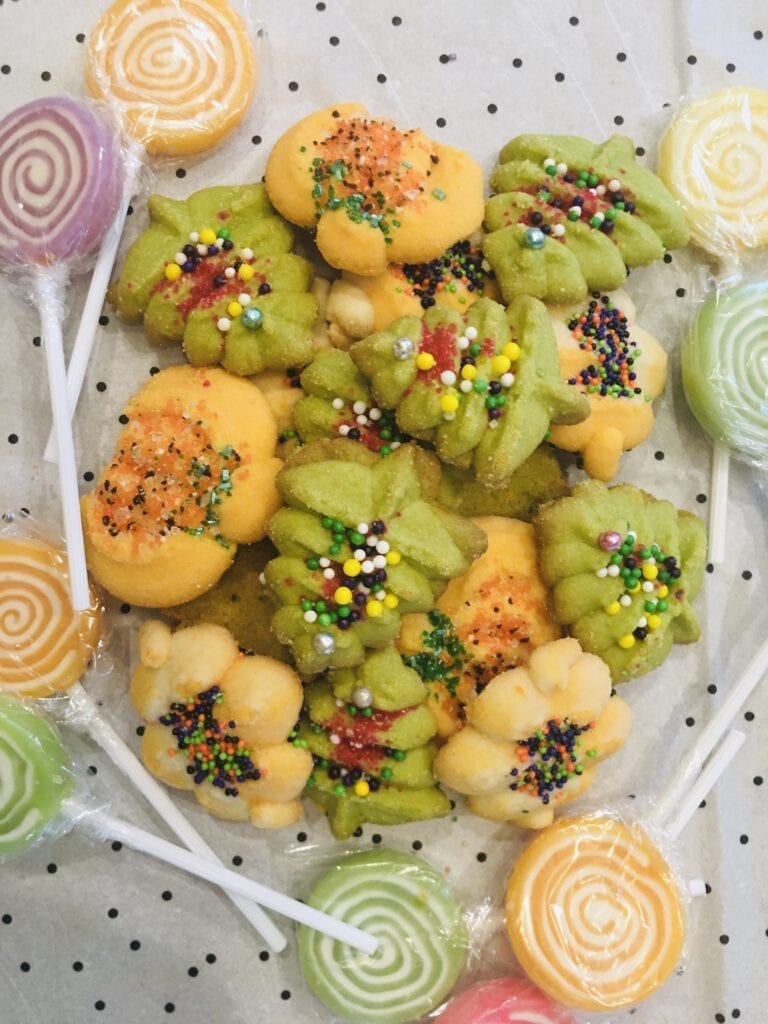 A plate of cookies and lollipops with different colors.