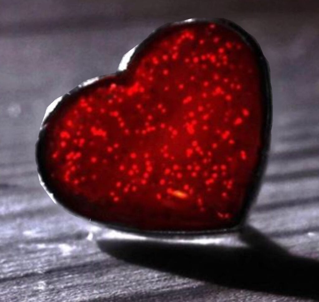 A red heart sitting on top of a wooden table.