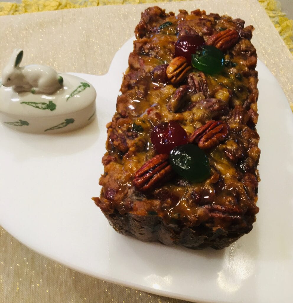 A loaf of bread with nuts on top and a bowl of dip.