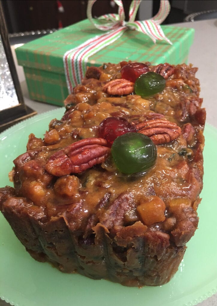 A piece of cake with nuts and fruit on top.